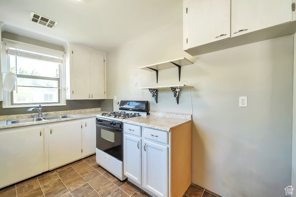 Kitchen featuring gas range, light countertops, and white cabinets