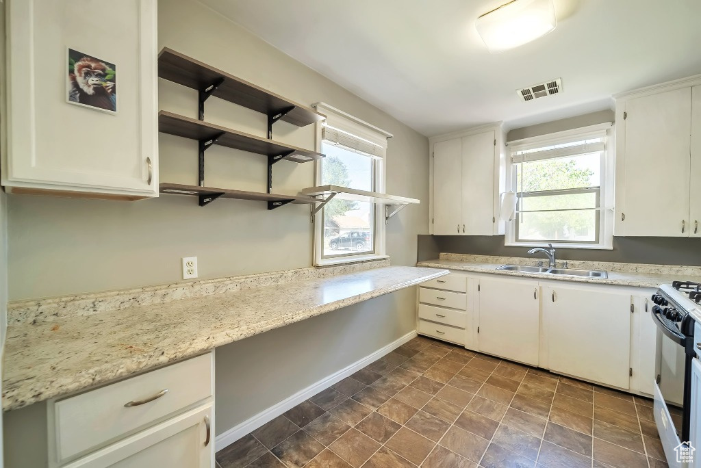 Kitchen featuring gas stove, white cabinetry, and open shelves