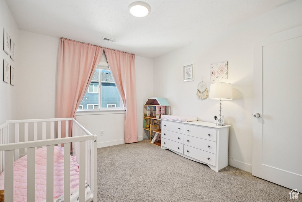 Carpeted bedroom with a nursery area and baseboards