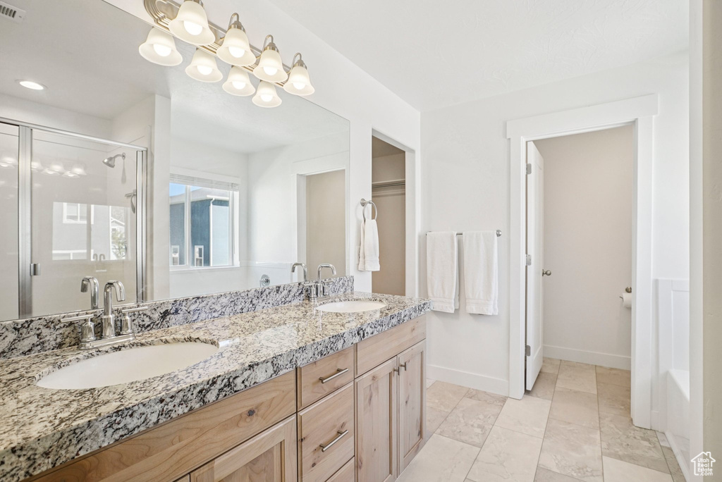 Full bath featuring a shower stall, double vanity, baseboards, and a tub