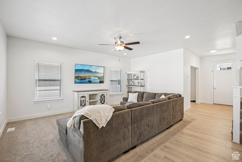 Living room with a ceiling fan, baseboards, recessed lighting, healthy amount of natural light, and light wood-style flooring