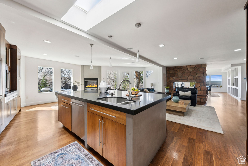 Kitchen featuring a multi sided fireplace, open floor plan, dark countertops, wood finished floors, and recessed lighting