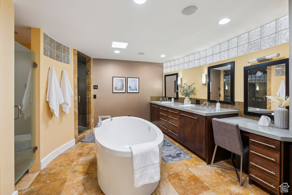 Bathroom featuring double vanity, a freestanding tub, a shower stall, and recessed lighting