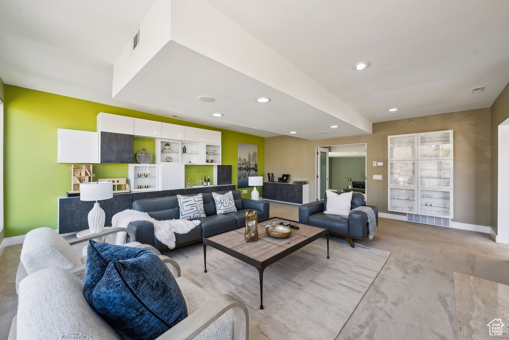 Living area with light carpet and recessed lighting