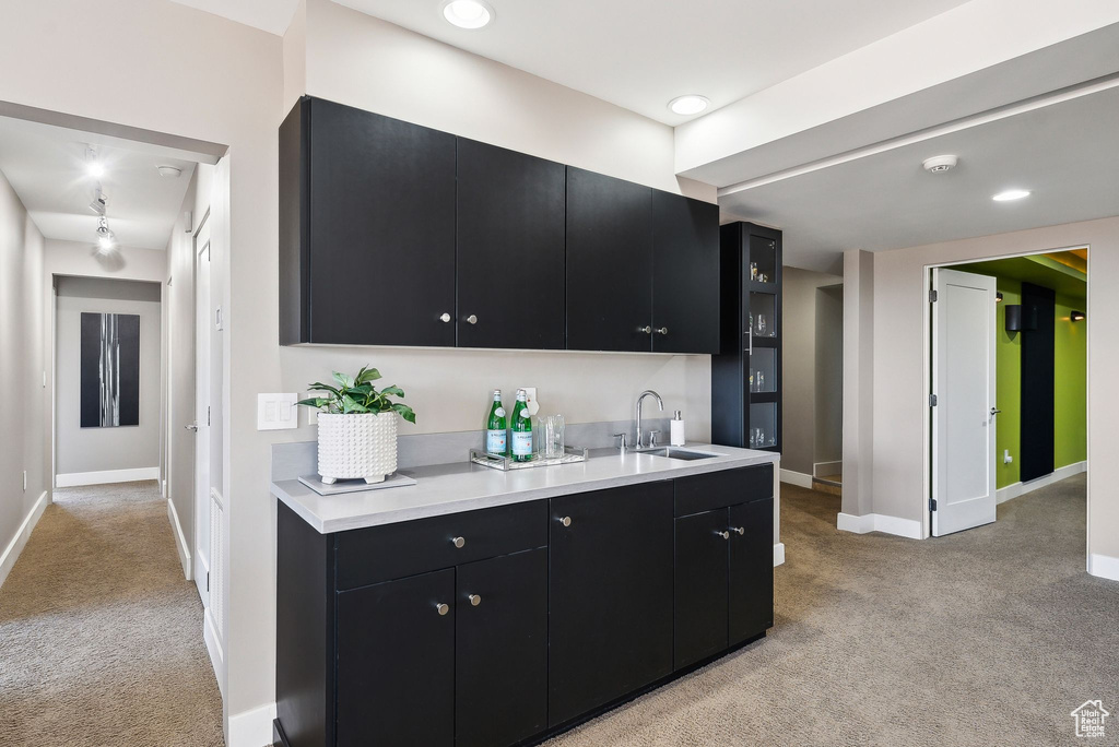 Kitchen featuring dark cabinets, light colored carpet, light countertops, and recessed lighting