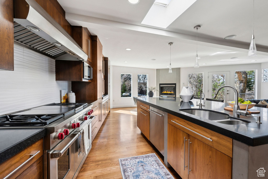 Kitchen with wall chimney exhaust hood, stainless steel appliances, open floor plan, healthy amount of natural light, and recessed lighting