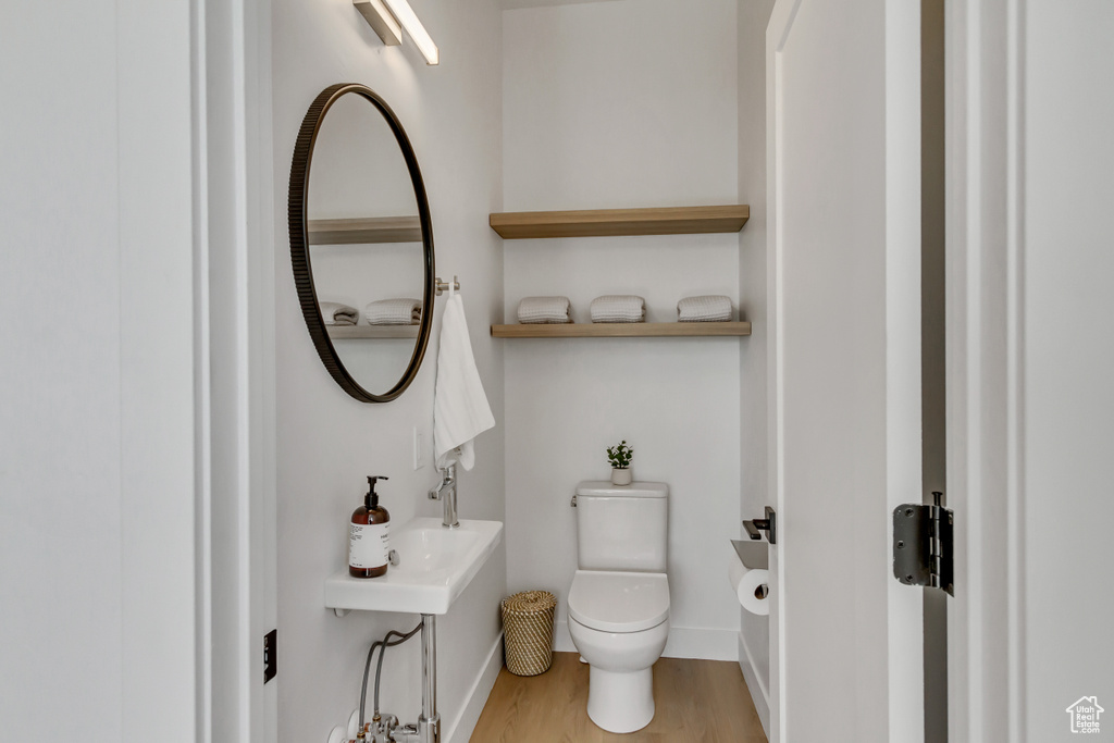 Half bathroom featuring wood finished floors and toilet