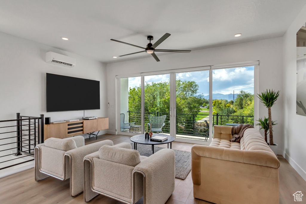 Living area with a ceiling fan, a wall mounted air conditioner, recessed lighting, and wood finished floors