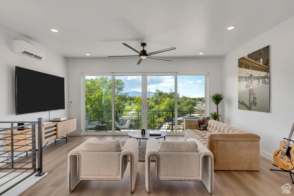 Living room featuring a wall unit AC, healthy amount of natural light, a ceiling fan, wood finished floors, and recessed lighting