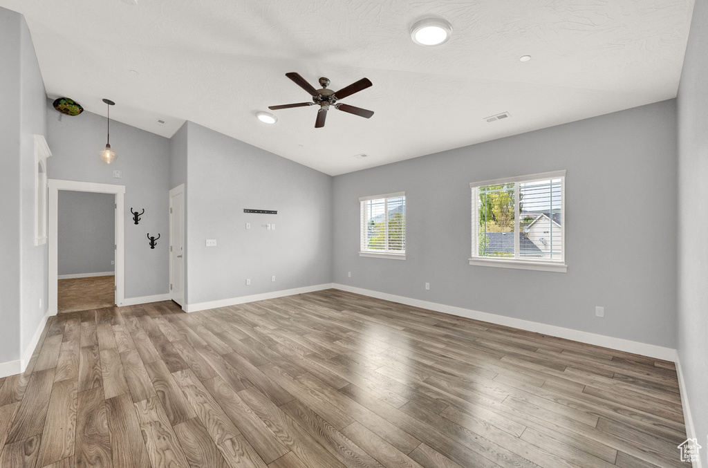 Unfurnished room with lofted ceiling, a ceiling fan, and wood finished floors