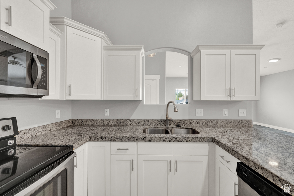 Kitchen featuring stainless steel appliances, white cabinetry, and arched walkways
