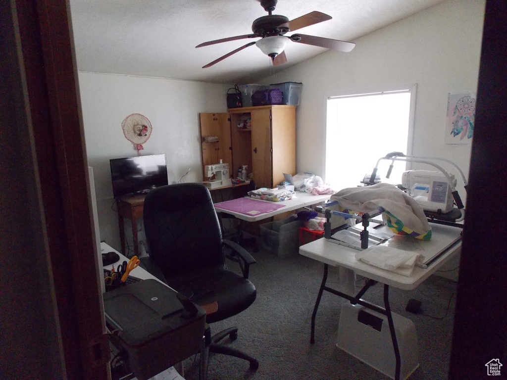 Carpeted office space with vaulted ceiling and a ceiling fan