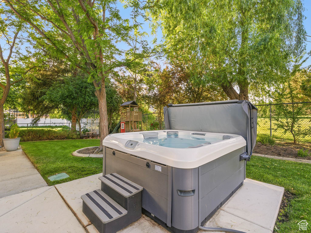View of patio with a hot tub and a playground