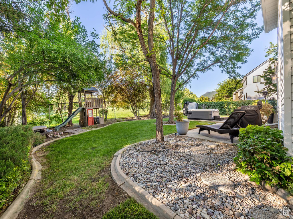 View of yard with a playground and a hot tub