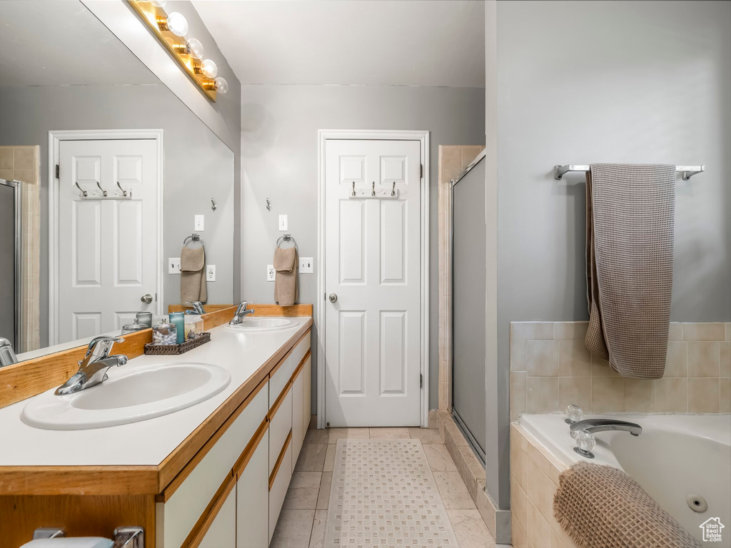 Bathroom featuring double vanity, a shower stall, and a tub with jets