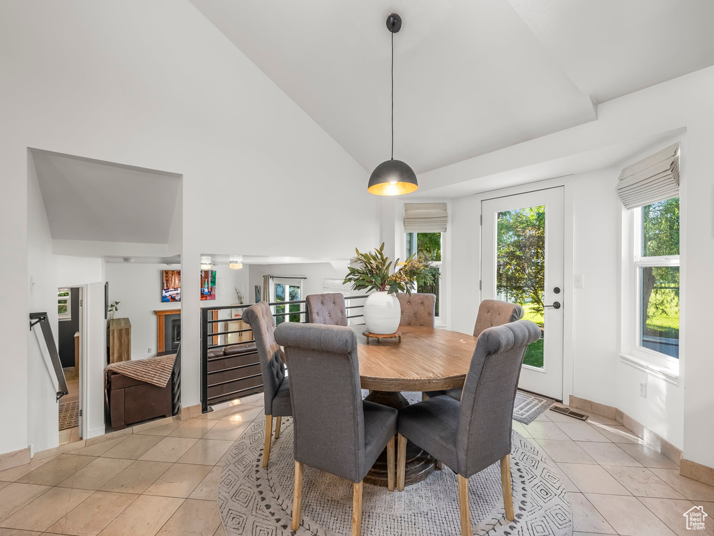 Dining area featuring light tile patterned floors and high vaulted ceiling