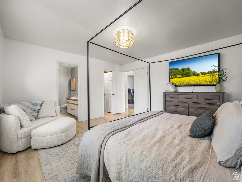 Bedroom with light wood-style floors and connected bathroom