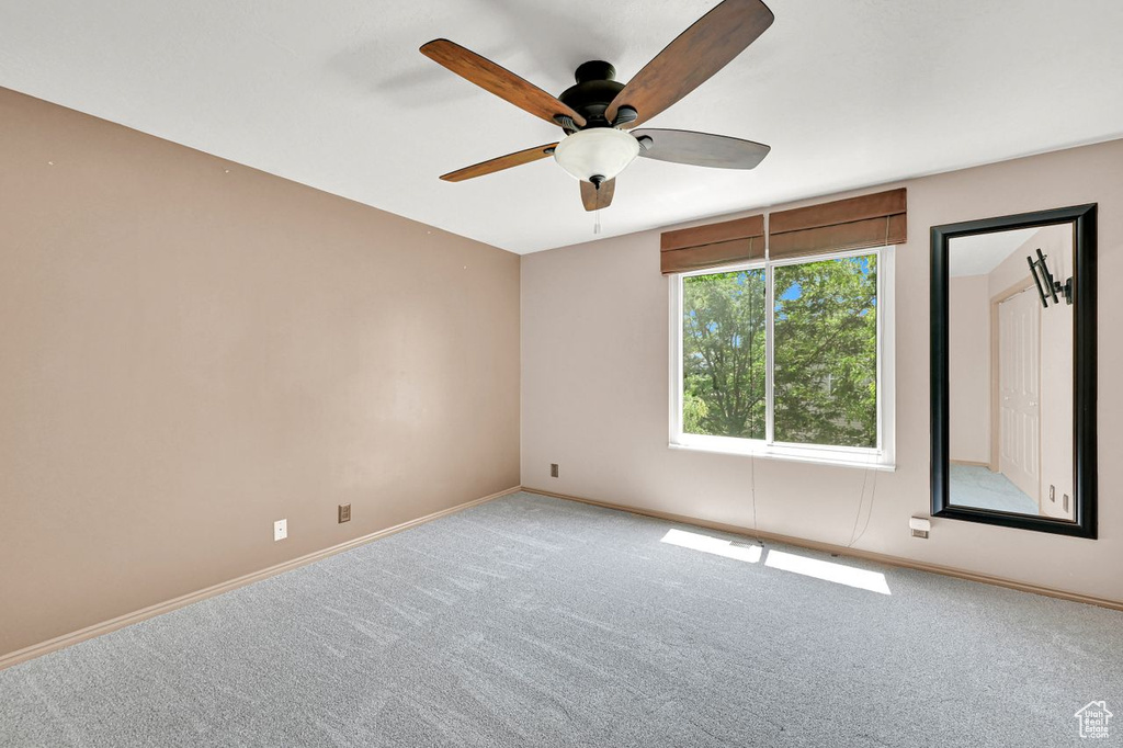 Carpeted spare room featuring a ceiling fan and baseboards