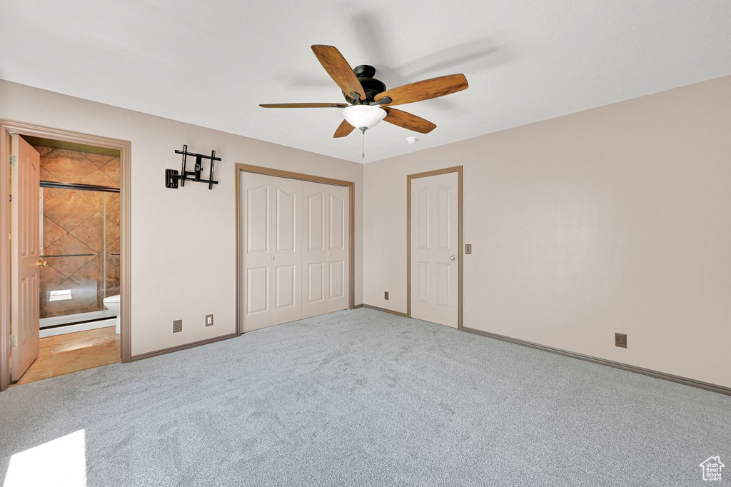 Unfurnished bedroom featuring carpet floors, connected bathroom, a ceiling fan, and a closet