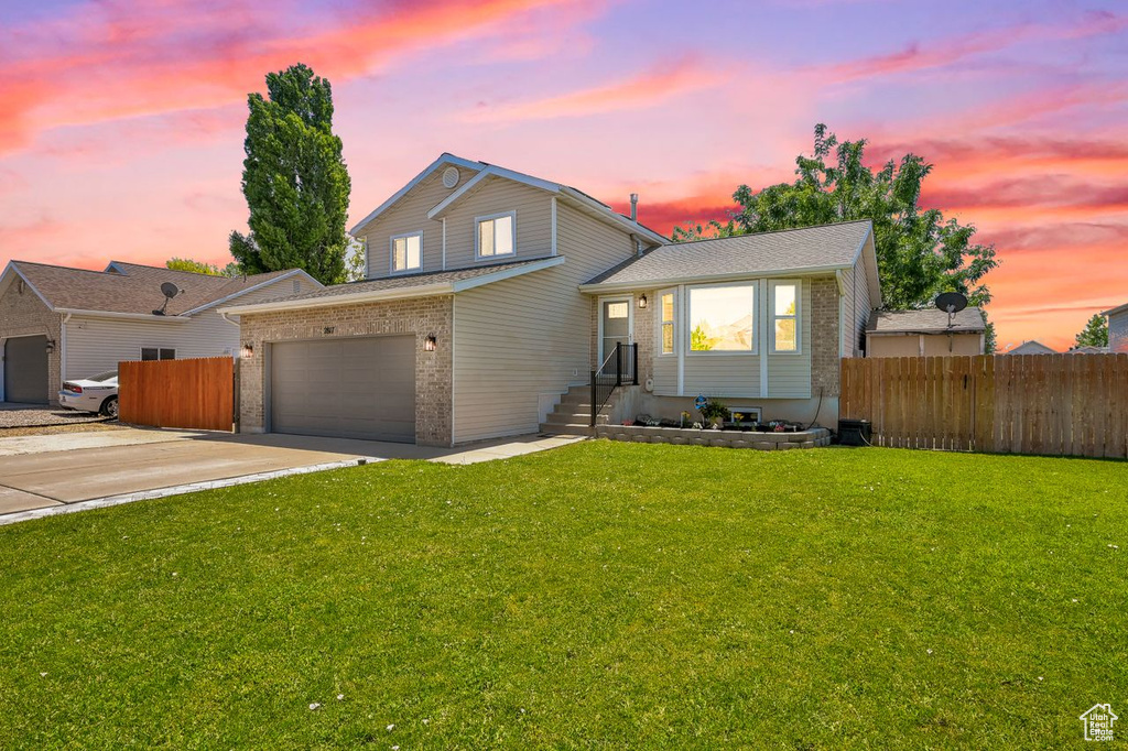Split level home featuring brick siding, a garage, and concrete driveway