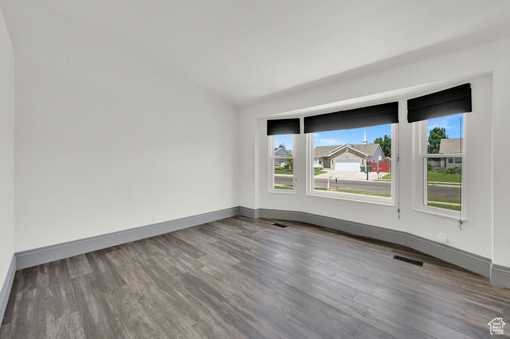 Spare room with wood finished floors and vaulted ceiling