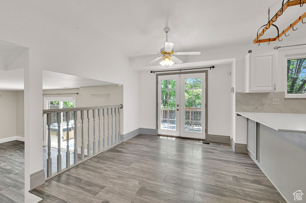 Unfurnished dining area with healthy amount of natural light, wood finished floors, ceiling fan, and french doors