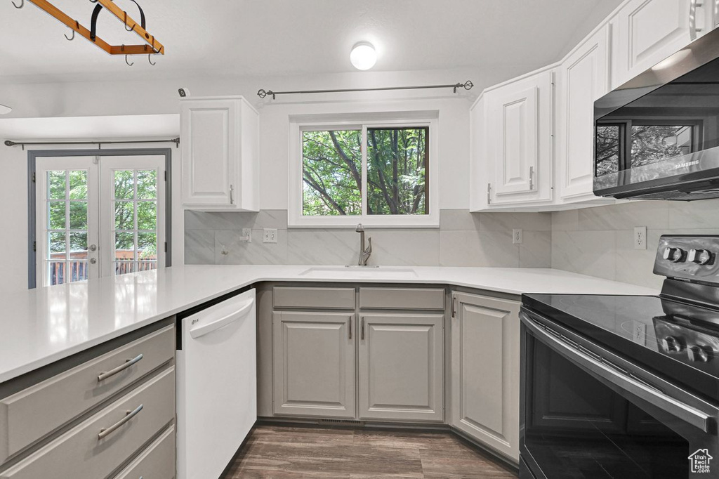 Kitchen with range with electric cooktop, stainless steel microwave, white dishwasher, gray cabinetry, and healthy amount of natural light