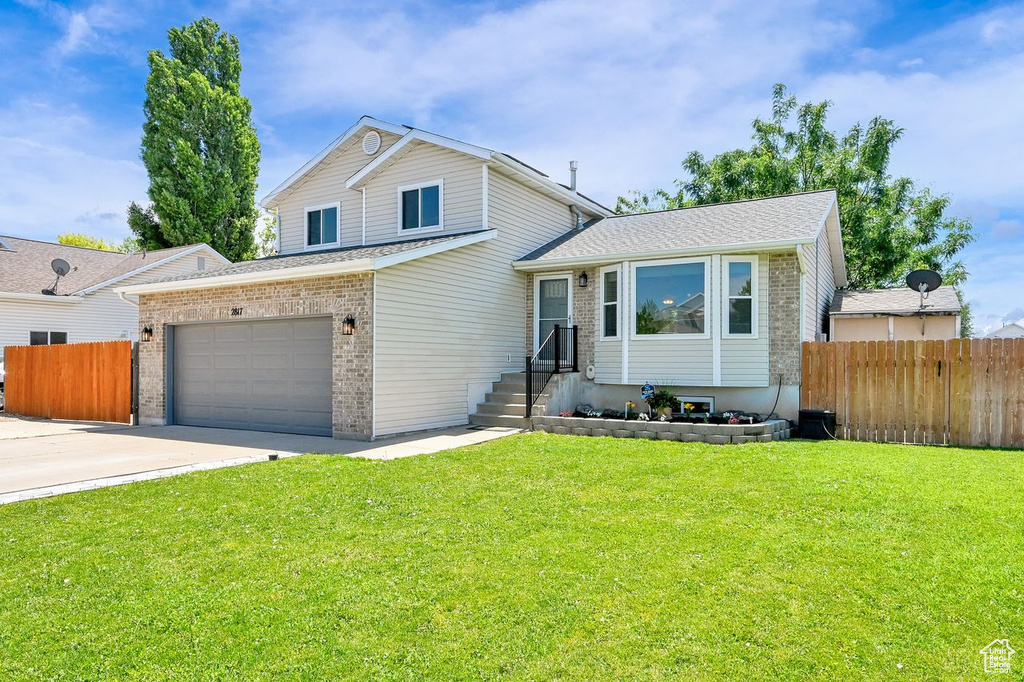 Tri-level home featuring brick siding, an attached garage, and driveway