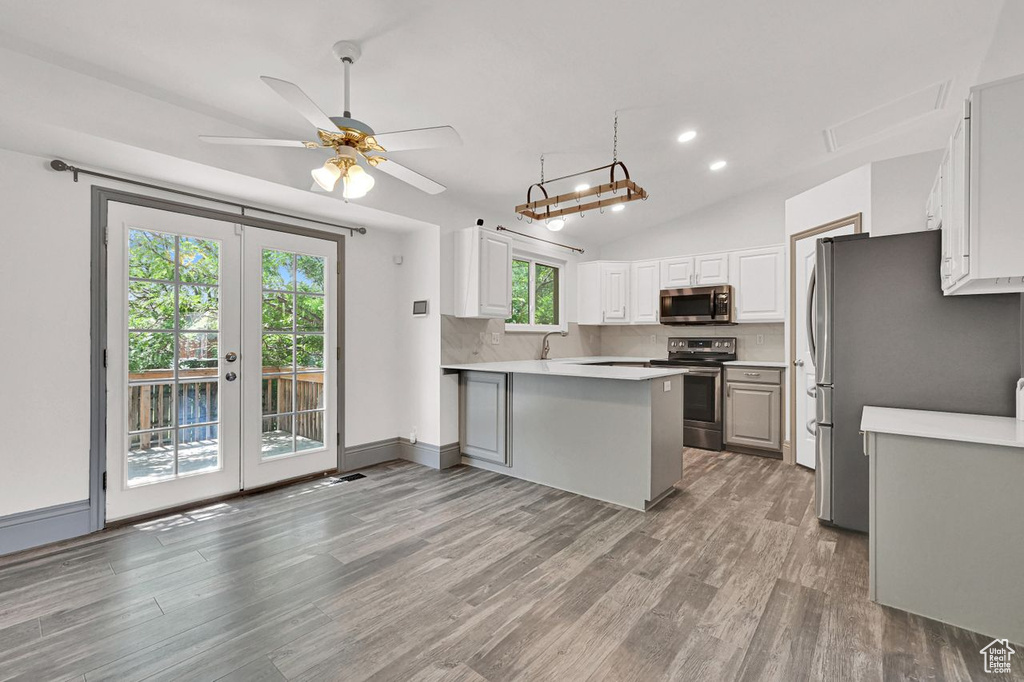 Kitchen featuring appliances with stainless steel finishes, light wood finished floors, light countertops, french doors, and lofted ceiling
