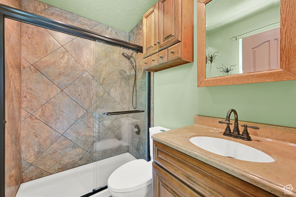 Full bath with a shower stall, vanity, and a textured ceiling