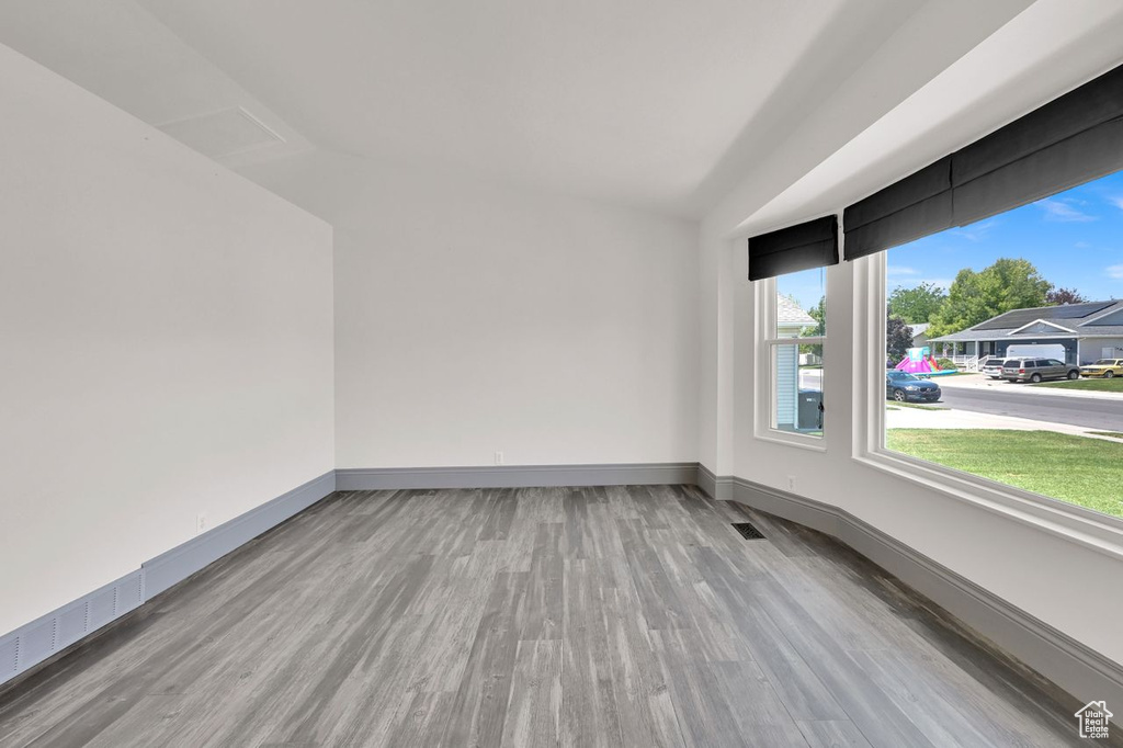 Empty room featuring wood finished floors and lofted ceiling