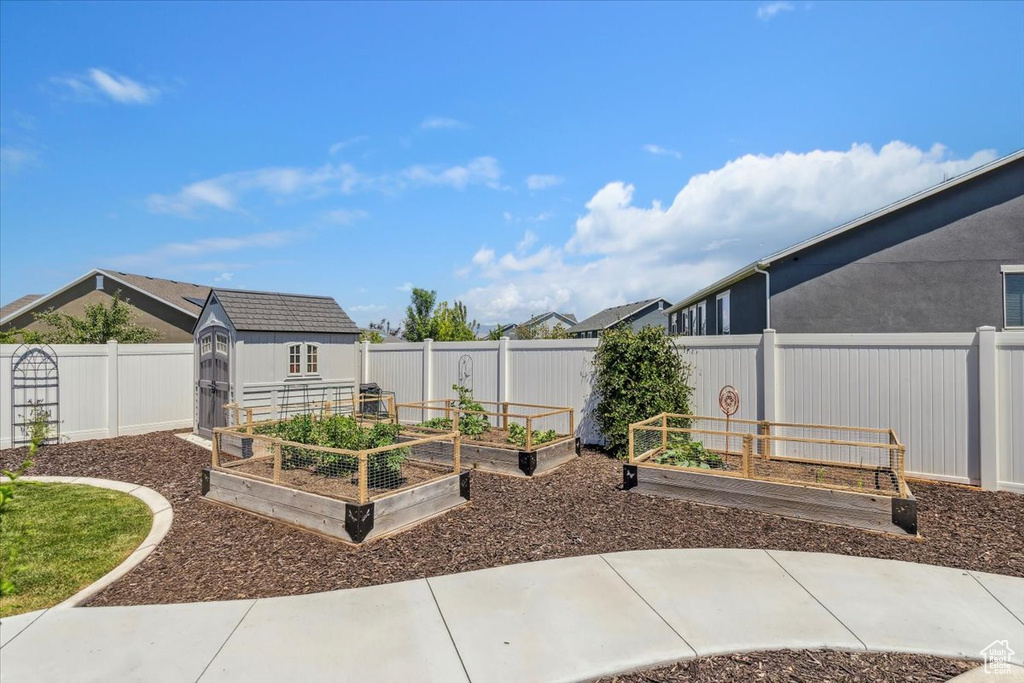 Fenced backyard with a storage unit and a garden