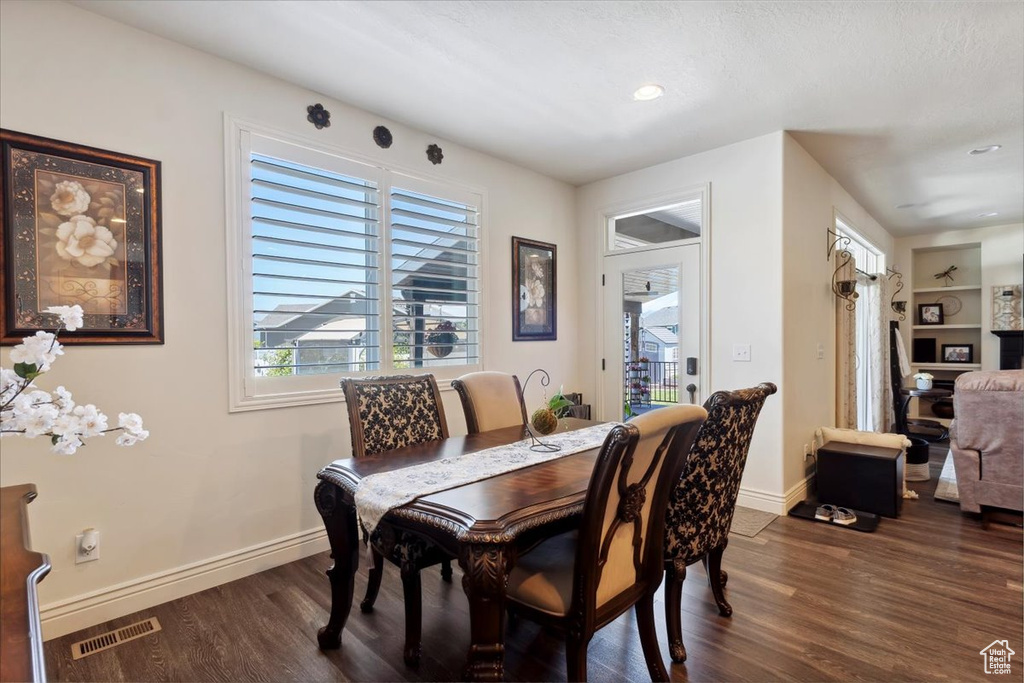 Dining room with dark wood-style floors, recessed lighting, and built in features