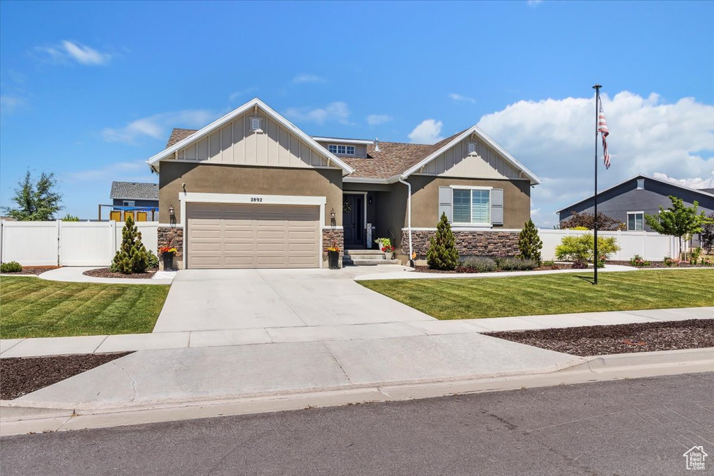 View of front of property with stucco siding, stone siding, an attached garage, and concrete driveway