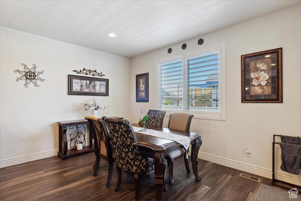 Dining space with dark wood finished floors and recessed lighting
