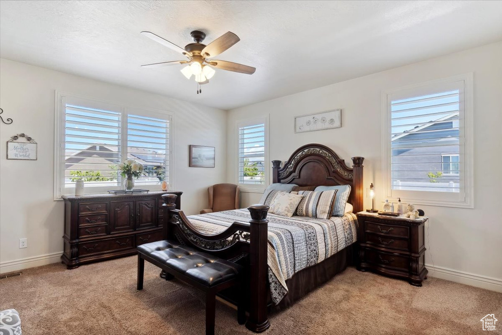 Bedroom with multiple windows, light colored carpet, and ceiling fan