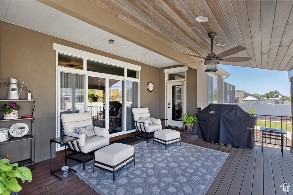 Wooden deck featuring grilling area, an outdoor hangout area, and a ceiling fan