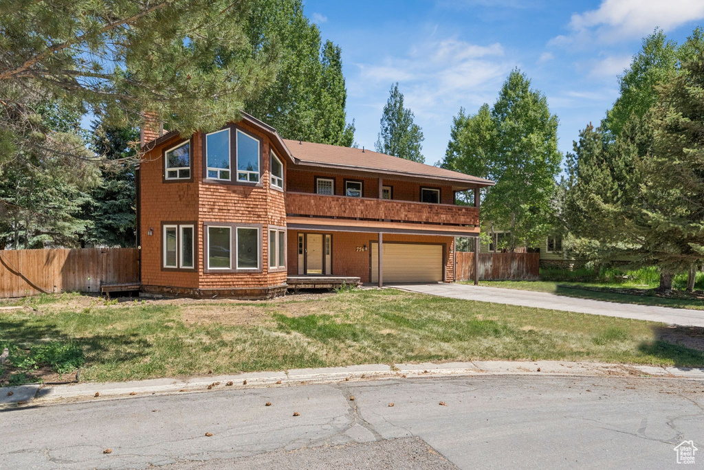 View of front facade featuring an attached garage, concrete driveway, a chimney, and covered porch