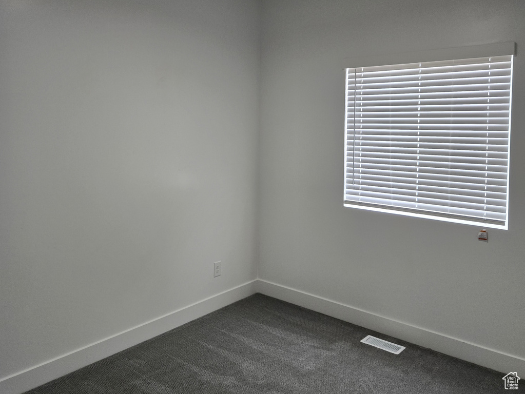 Spare room with dark carpet and baseboards