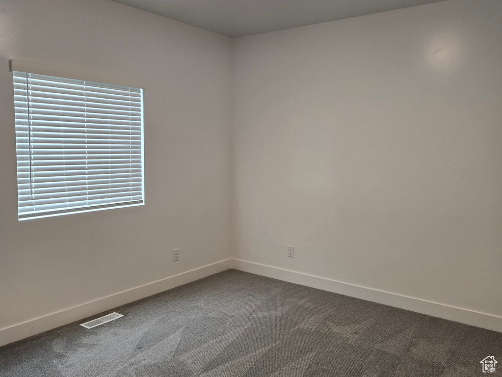 Empty room featuring baseboards, dark carpet, and a textured ceiling