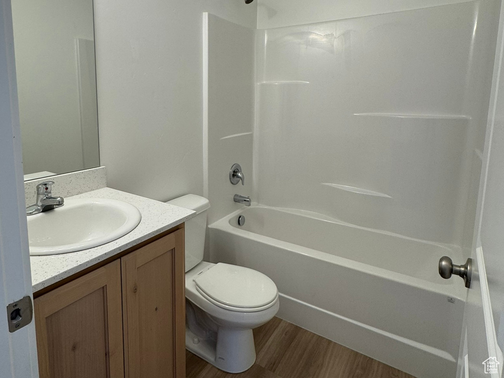 Bathroom with wood finished floors, shower / bath combination, vanity, toilet, and a textured ceiling