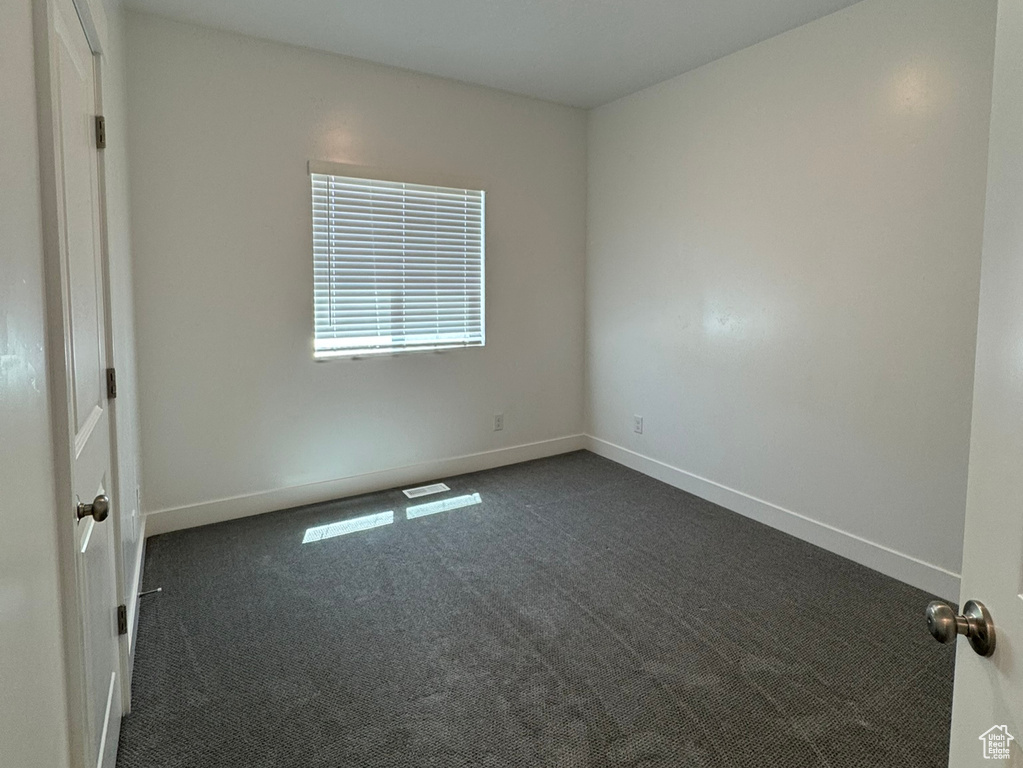 Spare room featuring dark colored carpet, baseboards, and a textured ceiling