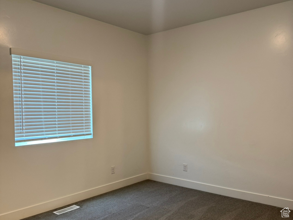 Spare room with dark carpet and baseboards