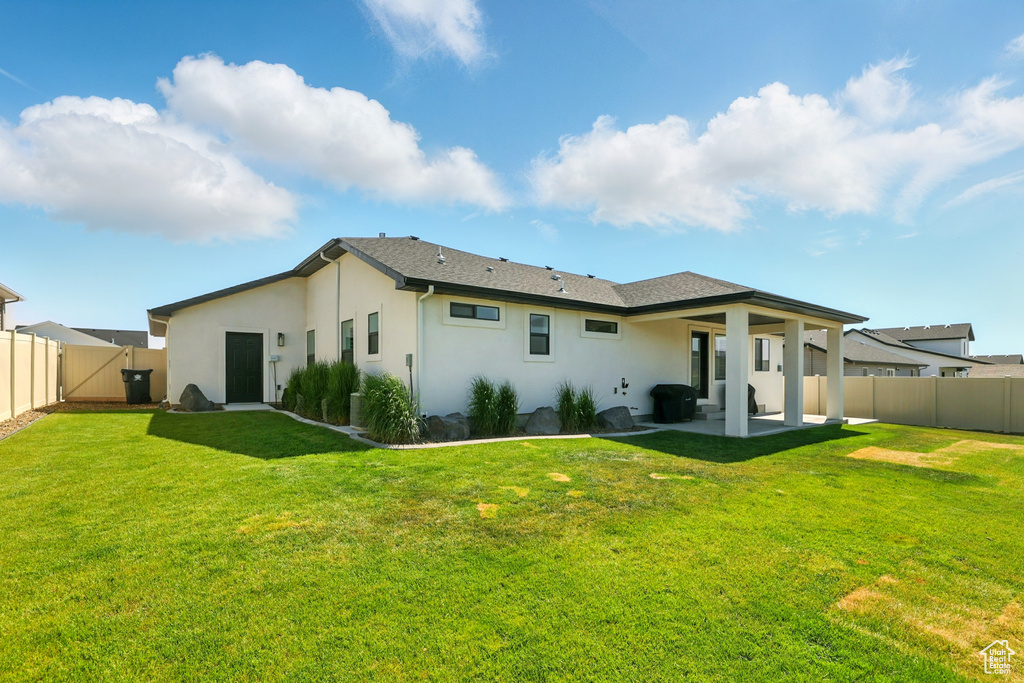 Rear view of house featuring stucco siding, a patio area, and a fenced backyard