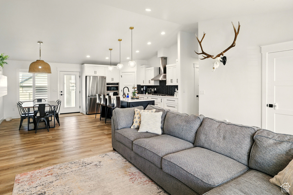 Living room featuring light wood finished floors, lofted ceiling, and recessed lighting