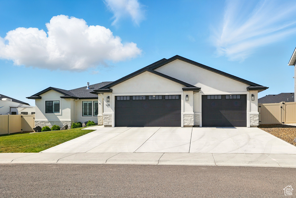 Ranch-style house featuring stone siding, a garage, stucco siding, and a gate