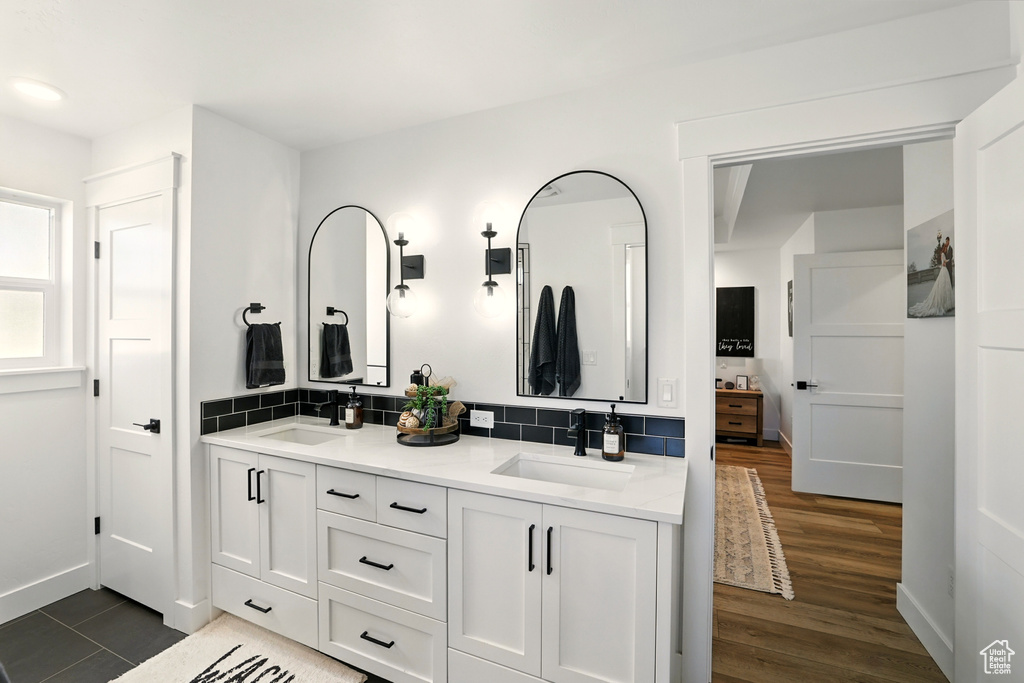 Full bath with double vanity, backsplash, and wood finished floors