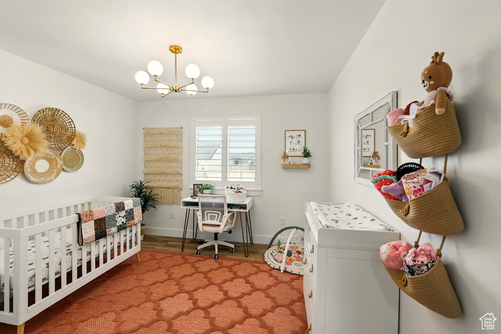 Bedroom with a chandelier, a crib, and wood finished floors