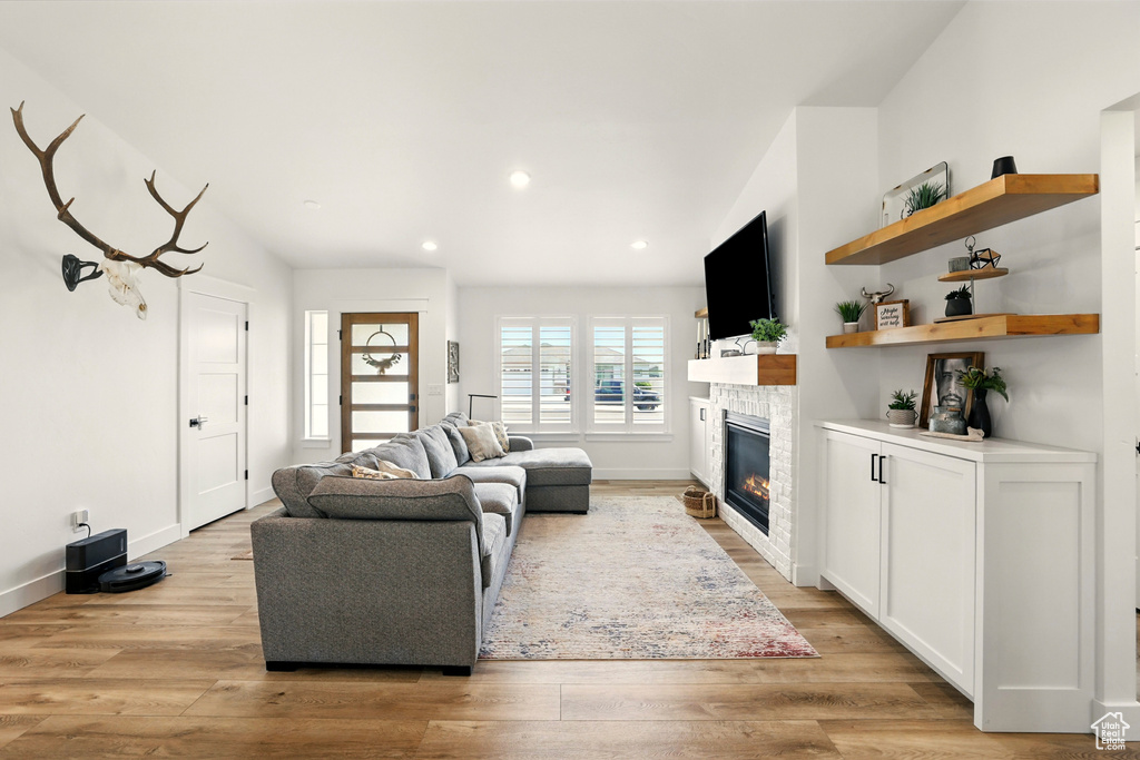 Living area featuring a glass covered fireplace, light wood finished floors, and recessed lighting