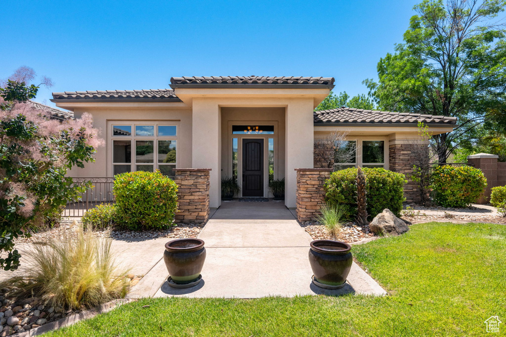 View of front facade with a tiled roof, stone siding, and stucco siding
